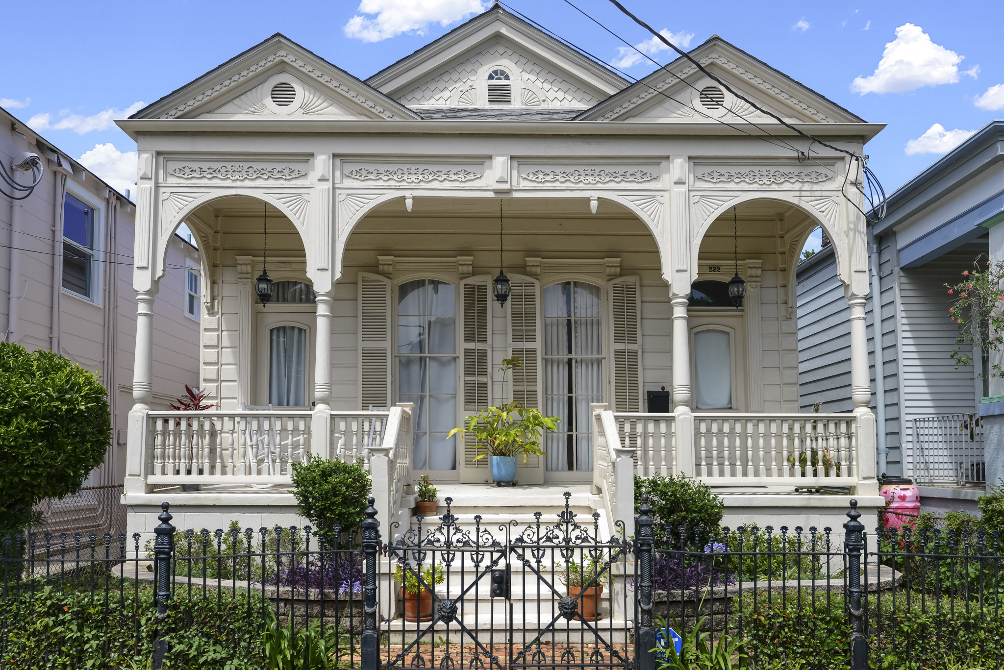 Cream double-gallery Victorian cottage with ornate millwork on an Uptown New Orleans street