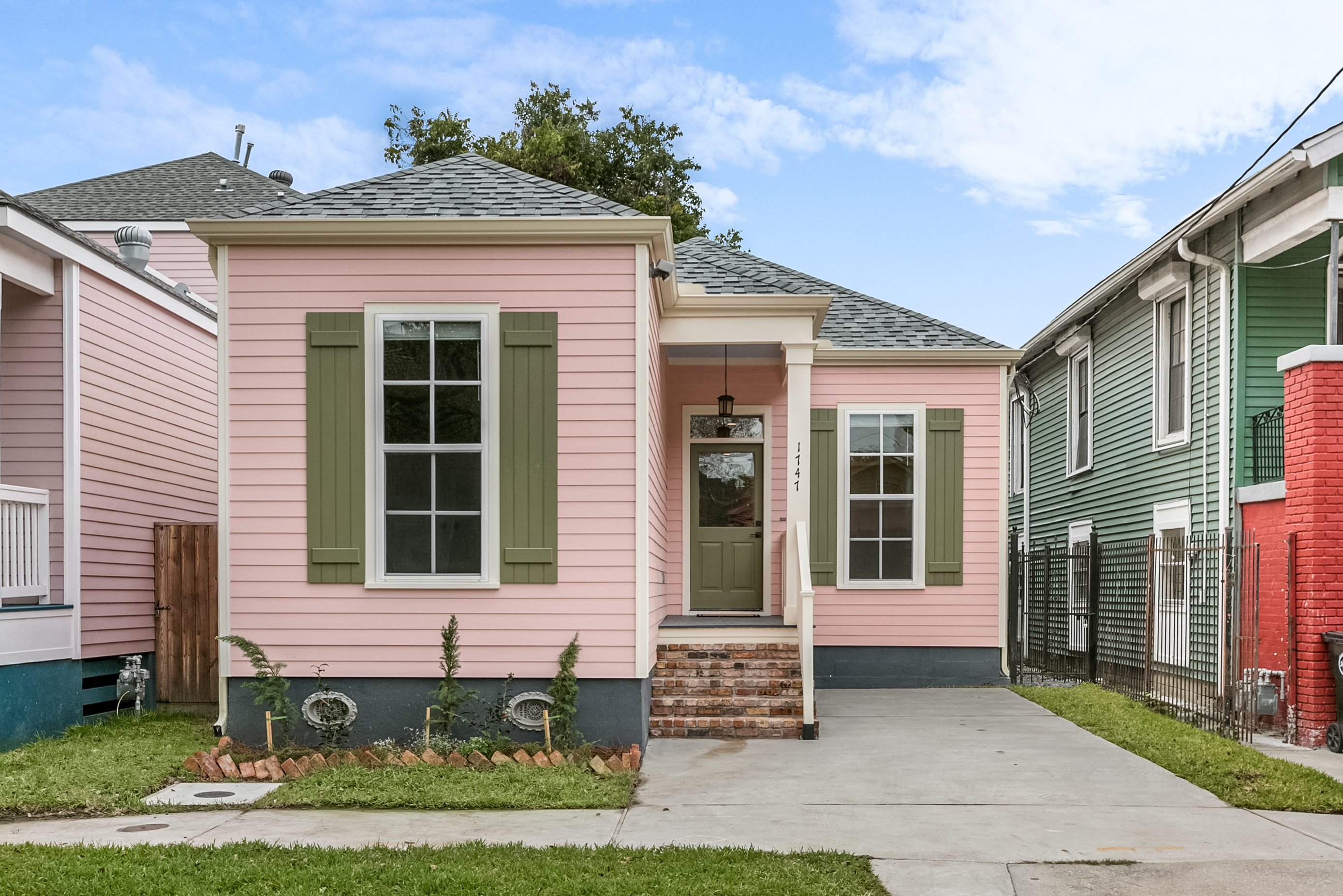 Renovated pink Creole cottage with green shutters and fresh landscaping in New Orleans