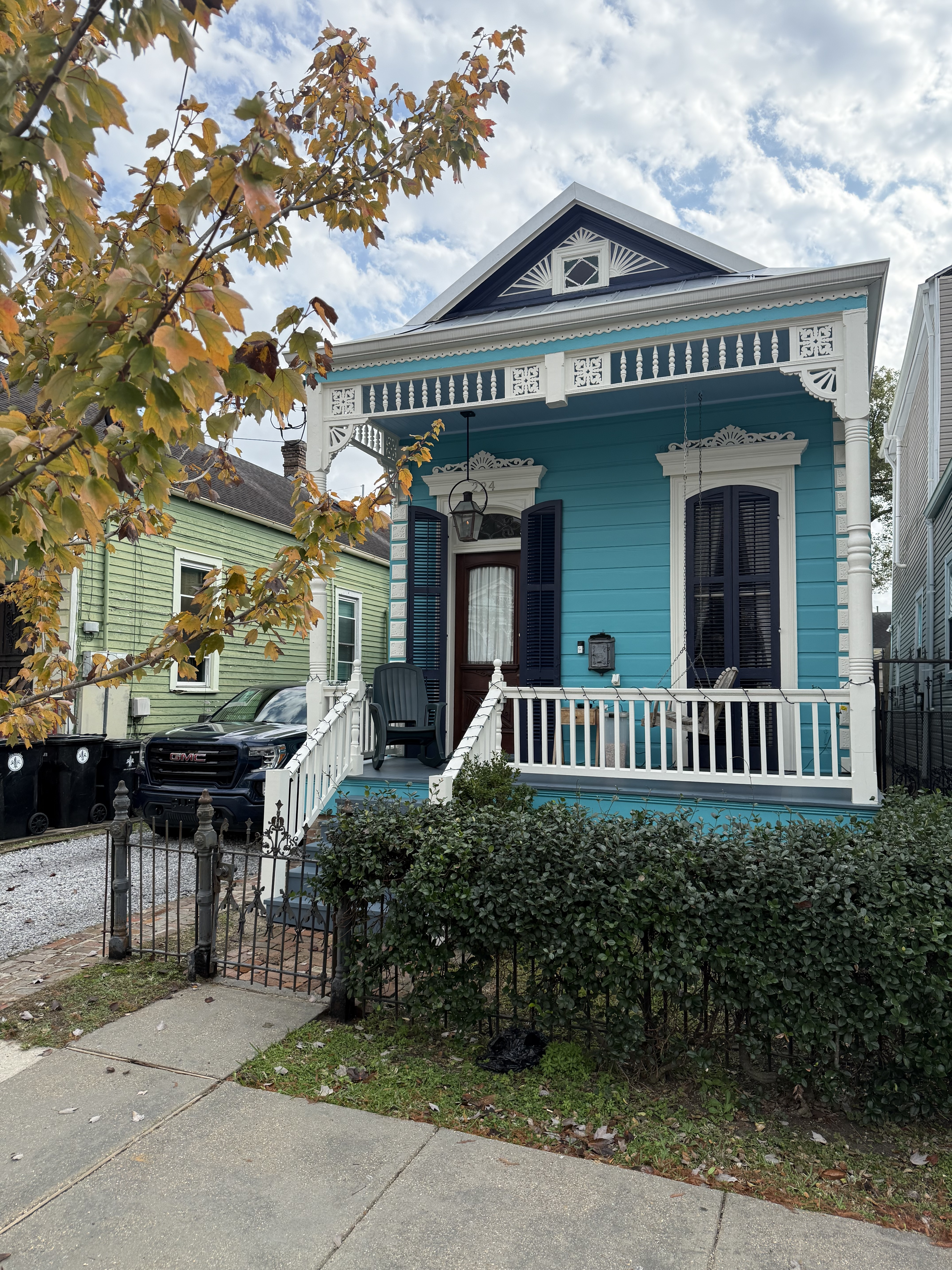 Restored teal Victorian shotgun cottage with gingerbread trim on a New Orleans street